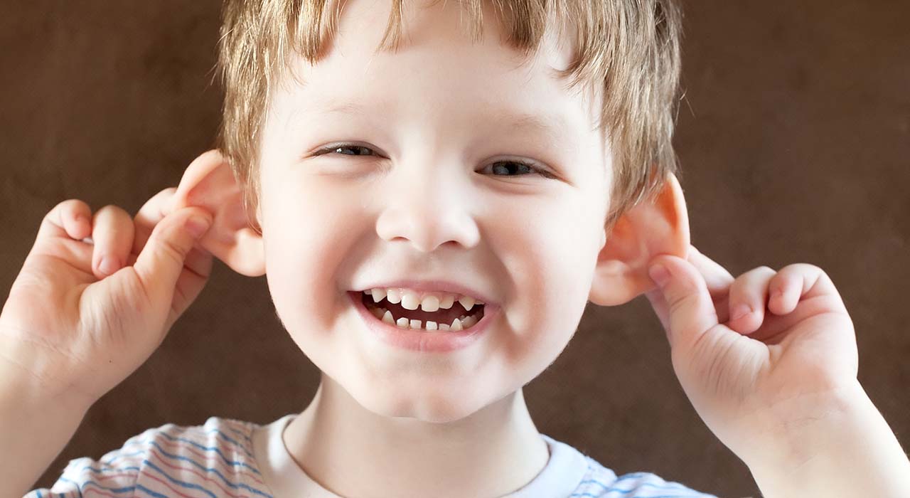 Happy Little boy, pulling himself on the ears